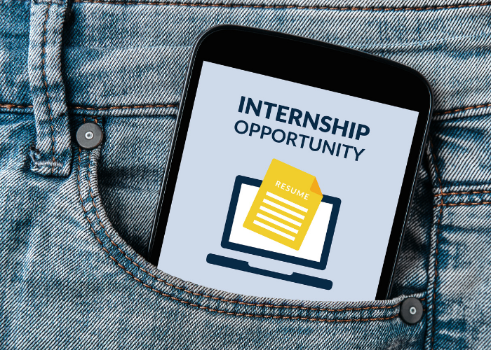 Celular no bolso de uma calça jeans exibindo a mensagem "Internship Opportunity" com ícone de currículo e computador.