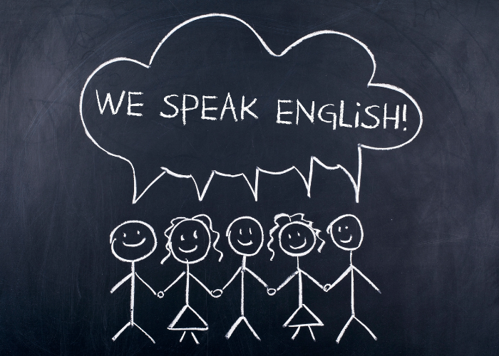 Desenho em lousa de cinco bonecos de palito com a frase “We speak English!” em um balão de fala, simbolizando aprendizado em grupo.