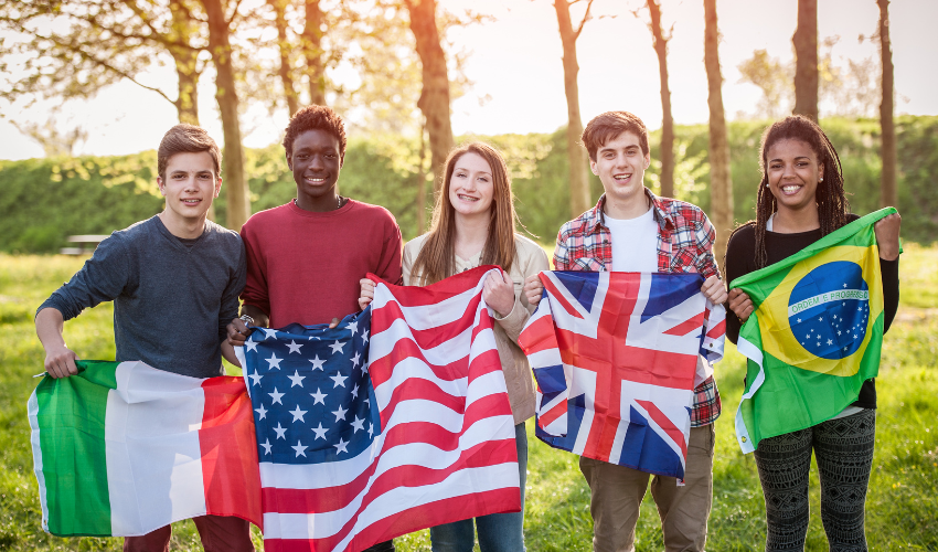 Grupo de jovens segurando bandeiras de diferentes países, incluindo Brasil, Estados Unidos e Reino Unido, simbolizando diversidade e aprendizado de inglês.