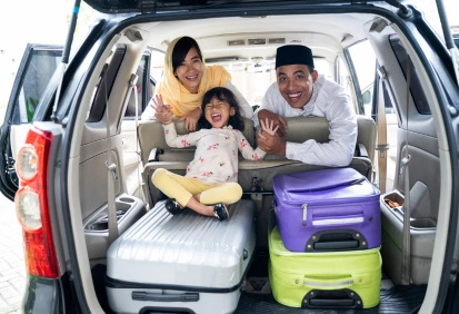 Família sorridente dentro de um carro com malas de viagem – imagem ideal para ensinar tempos verbais do futuro em inglês.